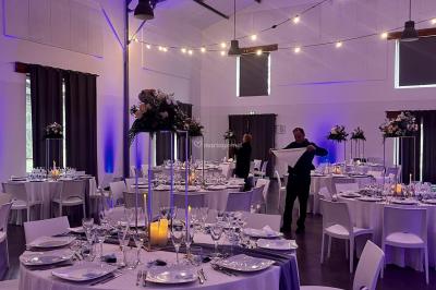 Une mariée en robe blanche applaudit devant un groupe de personnes dans un jardin lors d'une célébration.