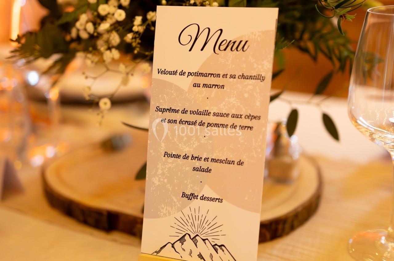 Carte de menu de mariage posée sur une table décorée avec des fleurs et des éléments en bois.