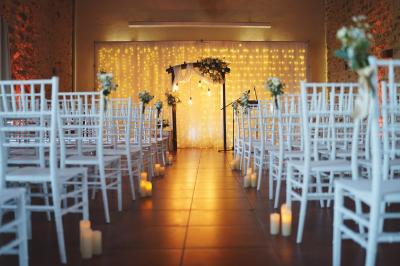 Une mariée en robe blanche applaudit devant un groupe de personnes dans un jardin lors d'une célébration.