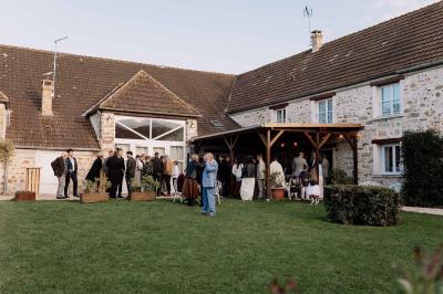 Une mariée en robe blanche applaudit devant un groupe de personnes dans un jardin lors d'une célébration.