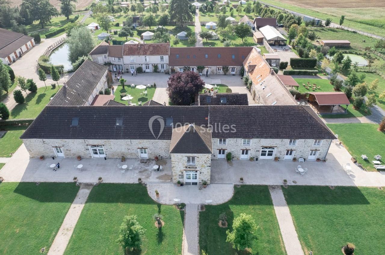 Vue aérienne d'un domaine avec bâtiments en pierre, jardin aménagé, allées et espaces verts environnants.