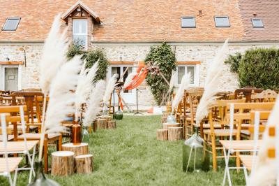 Une mariée en robe blanche applaudit devant un groupe de personnes dans un jardin lors d'une célébration.