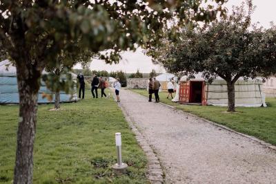 Une mariée en robe blanche applaudit devant un groupe de personnes dans un jardin lors d'une célébration.