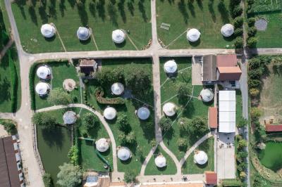 Une mariée en robe blanche applaudit devant un groupe de personnes dans un jardin lors d'une célébration.