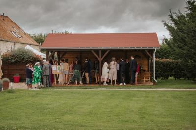 Une mariée en robe blanche applaudit devant un groupe de personnes dans un jardin lors d'une célébration.