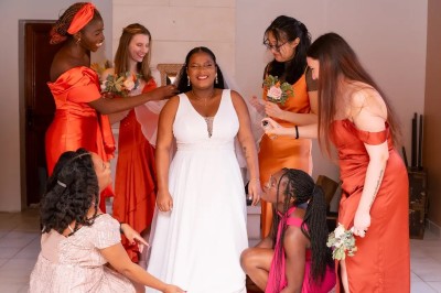 Un couple de mariés entouré de leurs témoins et demoiselles d'honneur posant en extérieur au coucher du soleil.