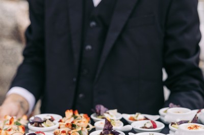 Un couple de mariés entouré de leurs témoins et demoiselles d'honneur posant en extérieur au coucher du soleil.