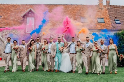 Un couple de mariés entouré de leurs témoins et demoiselles d'honneur posant en extérieur au coucher du soleil.