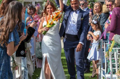 Un couple de mariés entouré de leurs témoins et demoiselles d'honneur posant en extérieur au coucher du soleil.