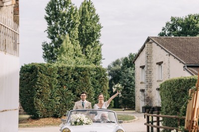 Un couple de mariés entouré de leurs témoins et demoiselles d'honneur posant en extérieur au coucher du soleil.