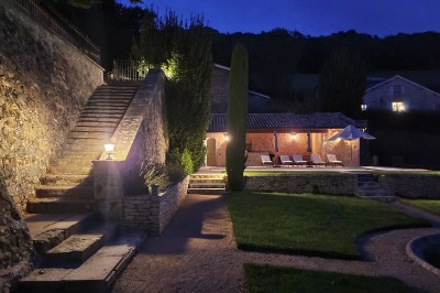 Miniature Location salle Beaujeu (Rhône) - Le Domaine de Vavril #32 Salle voûtée en pierre avec un sol en béton poli, éclairée par des lumières chaudes, et un vase de fleurs au centre.