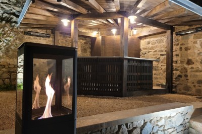 Miniature Location salle Beaujeu (Rhône) - Le Domaine de Vavril #36 Salle voûtée en pierre avec un sol en béton poli, éclairée par des lumières chaudes, et un vase de fleurs au centre.