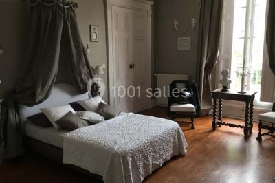 Couloir avec parquet en bois, murs verts décorés, table avec cadres et bougies, et rideaux verts aux fenêtres.