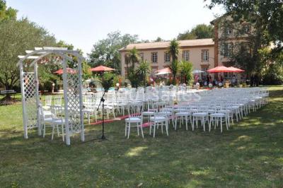 Couloir avec parquet en bois, murs verts décorés, table avec cadres et bougies, et rideaux verts aux fenêtres.