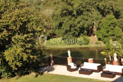 Couloir avec parquet en bois, murs verts décorés, table avec cadres et bougies, et rideaux verts aux fenêtres.