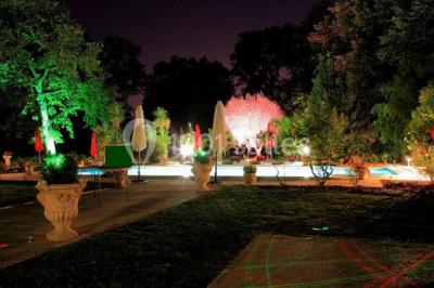 Couloir avec parquet en bois, murs verts décorés, table avec cadres et bougies, et rideaux verts aux fenêtres.