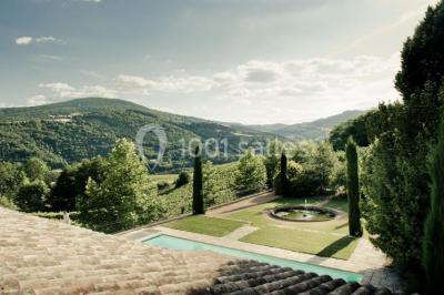 Groupe de personnes réunies en extérieur autour d'un bassin, avec vue sur des collines verdoyantes en arrière-plan.