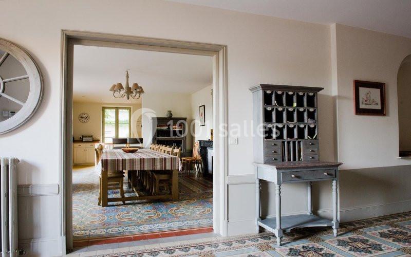 Salle à manger lumineuse avec une grande table en bois, un buffet à casiers et un sol en carreaux colorés.