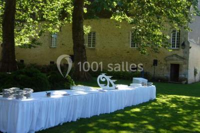 Façade d'un château illuminée par des lumières rouges, avec des drapeaux et des spectateurs en arrière-plan.
