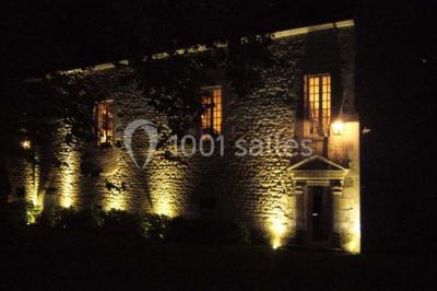 Façade d'un château illuminée par des lumières rouges, avec des drapeaux et des spectateurs en arrière-plan.