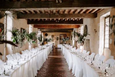 Façade d'un château illuminée par des lumières rouges, avec des drapeaux et des spectateurs en arrière-plan.