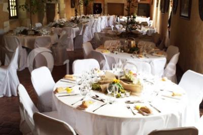 Façade d'un château illuminée par des lumières rouges, avec des drapeaux et des spectateurs en arrière-plan.