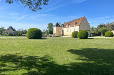 Miniature Location salle Pouilly-sur-Loire (Nièvre) - Château des Granges #25 Grand jardin verdoyant avec pelouse, arbustes taillés et bâtiments en pierre sous un ciel bleu dégagé.