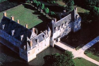 Façade d'un château illuminée par des lumières rouges, avec des drapeaux et des spectateurs en arrière-plan.
