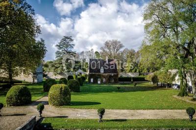 Façade d'un château illuminée par des lumières rouges, avec des drapeaux et des spectateurs en arrière-plan.