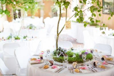 Façade d'un château illuminée par des lumières rouges, avec des drapeaux et des spectateurs en arrière-plan.