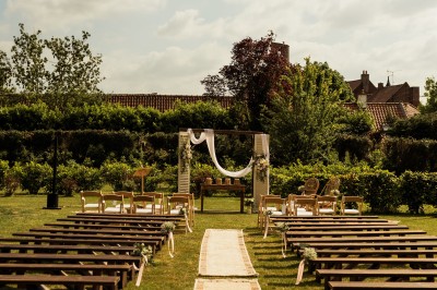 Salle de réception décorée avec des tables rondes dressées, des fleurs colorées et un mur de briques apparentes.