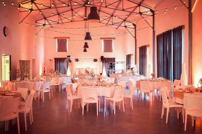 Cour extérieure éclairée par des guirlandes lumineuses, avec des invités rassemblés près de tables hautes.