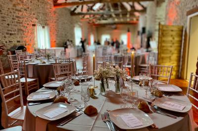Cour extérieure éclairée par des guirlandes lumineuses, avec des invités rassemblés près de tables hautes.