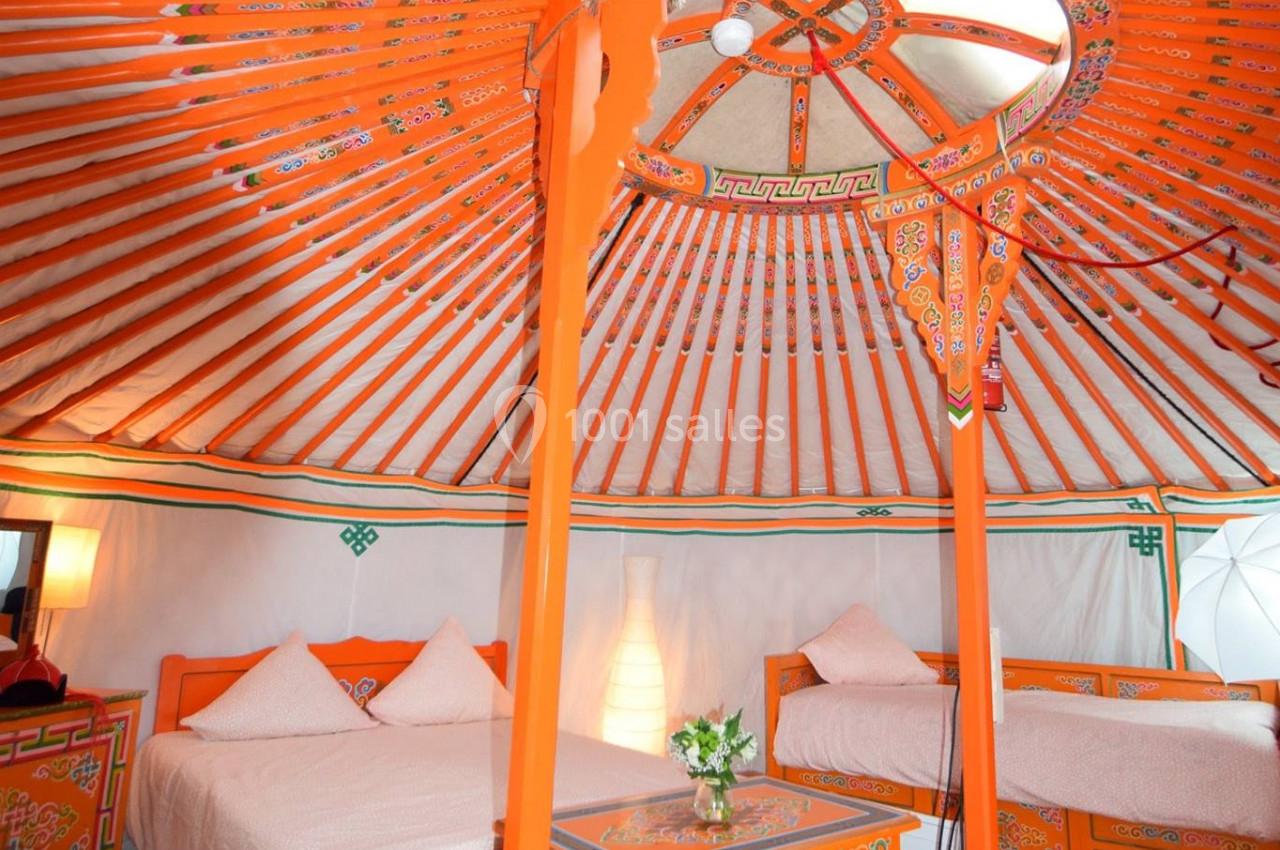 Intérieur d'une yourte traditionnelle avec lits, mobilier en bois peint et décorations colorées sous une structure…