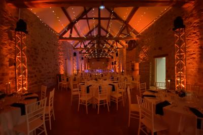 Cour extérieure éclairée par des guirlandes lumineuses, avec des invités rassemblés près de tables hautes.