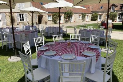 Cour extérieure éclairée par des guirlandes lumineuses, avec des invités rassemblés près de tables hautes.
