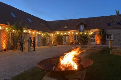 Cour extérieure éclairée par des guirlandes lumineuses, avec des invités rassemblés près de tables hautes.