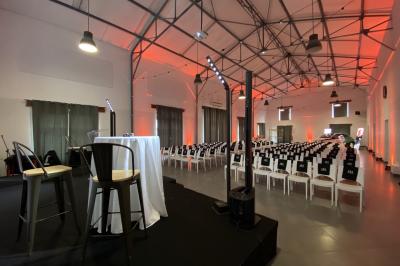 Cour extérieure éclairée par des guirlandes lumineuses, avec des invités rassemblés près de tables hautes.