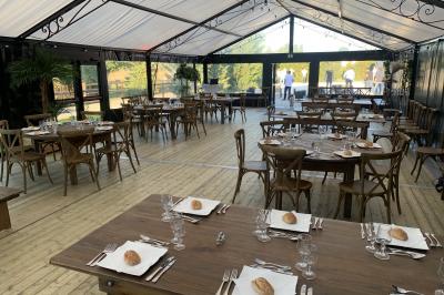 Cour extérieure éclairée par des guirlandes lumineuses, avec des invités rassemblés près de tables hautes.