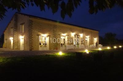 Cour extérieure éclairée par des guirlandes lumineuses, avec des invités rassemblés près de tables hautes.