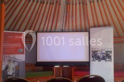 Cour extérieure éclairée par des guirlandes lumineuses, avec des invités rassemblés près de tables hautes.