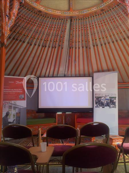 Écran de projection blanc entouré de deux kakémonos dans une salle décorée de motifs traditionnels colorés.