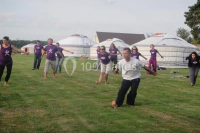 Cour extérieure éclairée par des guirlandes lumineuses, avec des invités rassemblés près de tables hautes.