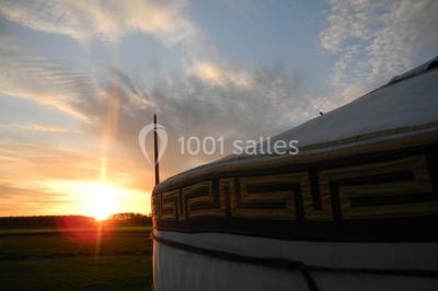 Cour extérieure éclairée par des guirlandes lumineuses, avec des invités rassemblés près de tables hautes.