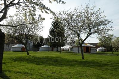 Cour extérieure éclairée par des guirlandes lumineuses, avec des invités rassemblés près de tables hautes.