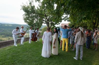 Table en pierre sous une voûte en pierre, avec un pot de fleurs et des outils anciens accrochés au mur.