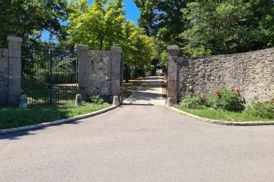 Table en pierre sous une voûte en pierre, avec un pot de fleurs et des outils anciens accrochés au mur.