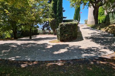 Table en pierre sous une voûte en pierre, avec un pot de fleurs et des outils anciens accrochés au mur.