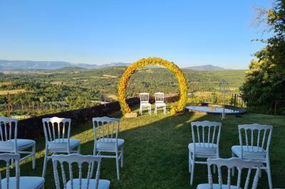 Table en pierre sous une voûte en pierre, avec un pot de fleurs et des outils anciens accrochés au mur.