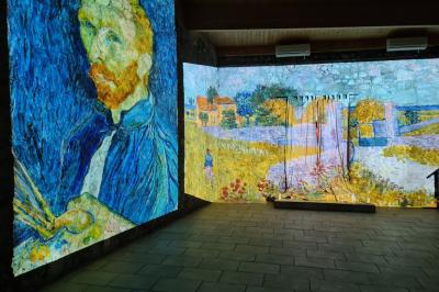 Table en pierre sous une voûte en pierre, avec un pot de fleurs et des outils anciens accrochés au mur.